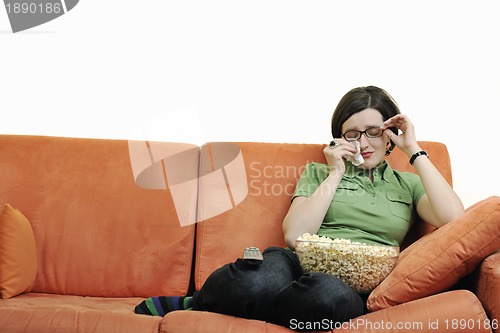 Image of young woman eat popcorn on orange sofa