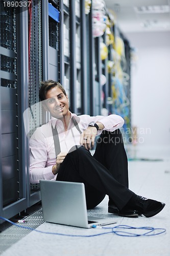 Image of businessman with laptop in network server room