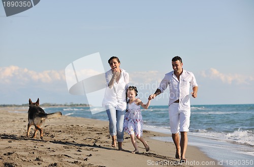 Image of happy family playing with dog on beach