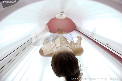 Image of Beautiful young woman tanning in solarium