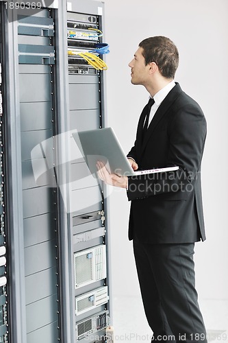 Image of businessman with laptop in network server room