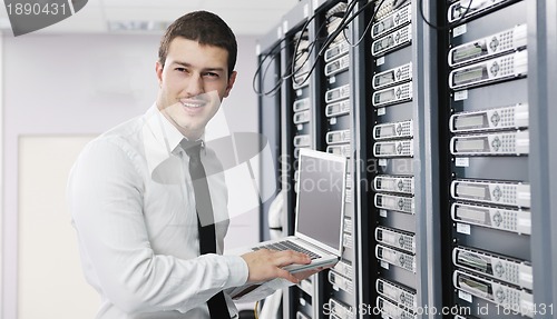 Image of businessman with laptop in network server room