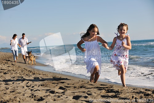 Image of happy family playing with dog on beach