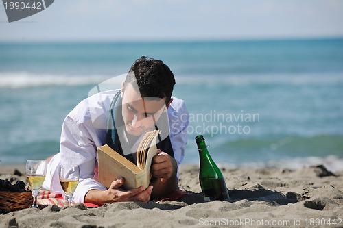 Image of man reading book at beach