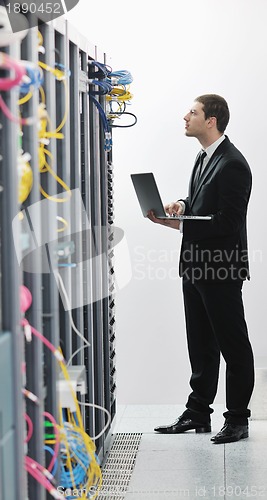 Image of businessman with laptop in network server room