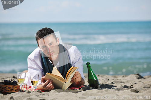 Image of man reading book at beach