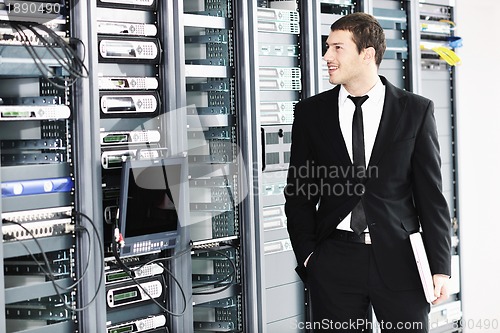 Image of businessman with laptop in network server room