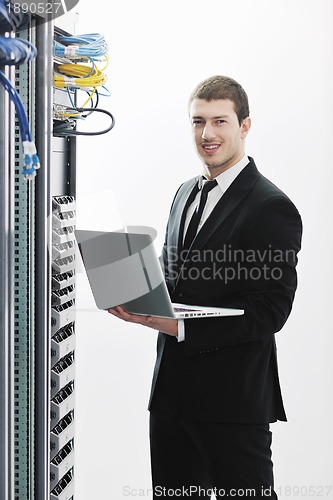 Image of businessman with laptop in network server room