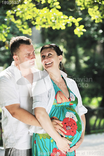 Image of Happy pregnant couple at beautiful sunny day in park