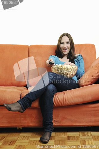 Image of young woman eat popcorn on orange sofa