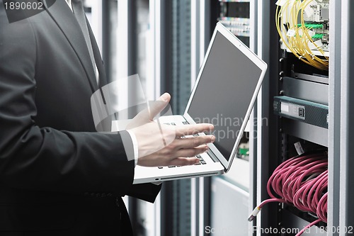 Image of businessman with laptop in network server room