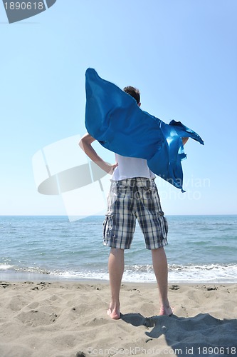 Image of funny superhero standing on beach