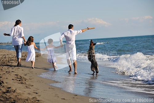 Image of happy family playing with dog on beach