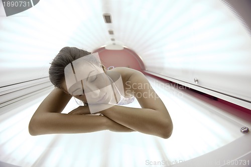 Image of Beautiful young woman tanning in solarium