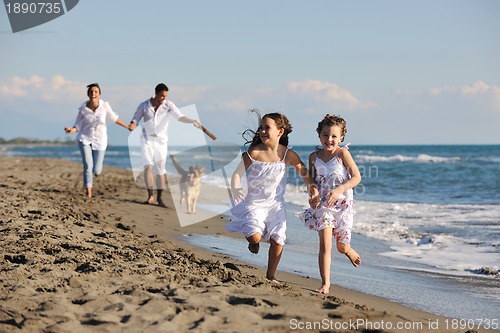 Image of happy family playing with dog on beach