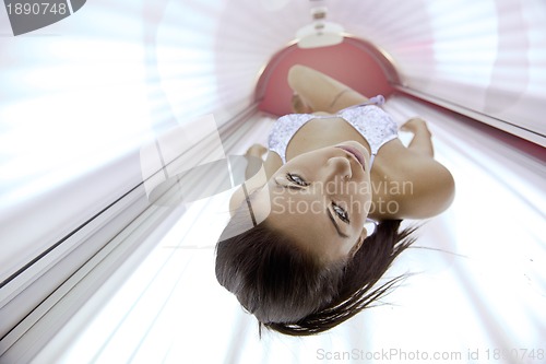 Image of Beautiful young woman tanning in solarium