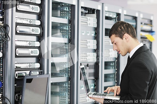 Image of businessman with laptop in network server room