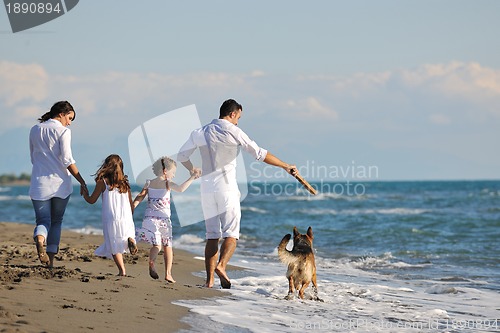 Image of happy family playing with dog on beach