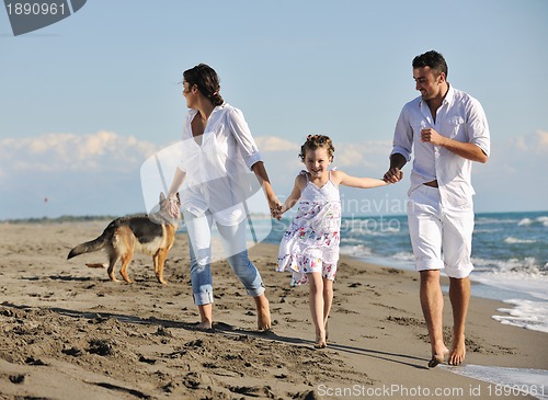 Image of happy family playing with dog on beach