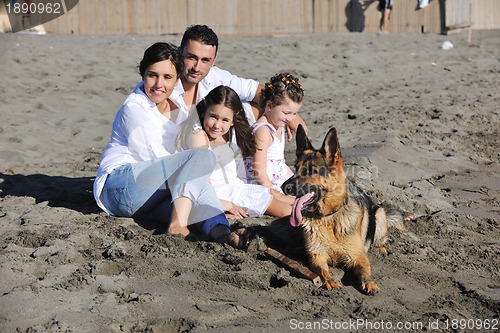 Image of happy family playing with dog on beach