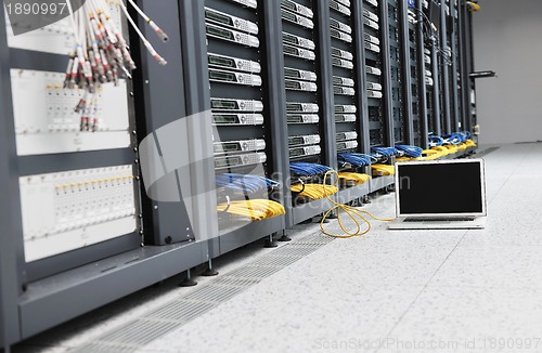 Image of businessman with laptop in network server room