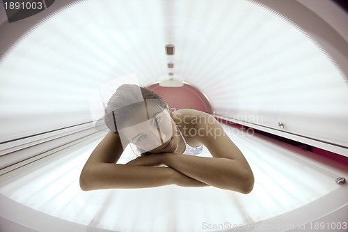 Image of Beautiful young woman tanning in solarium