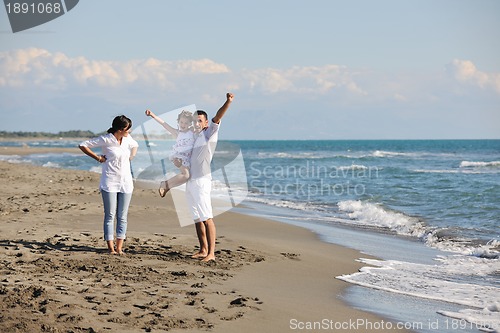 Image of happy family playing with dog on beach