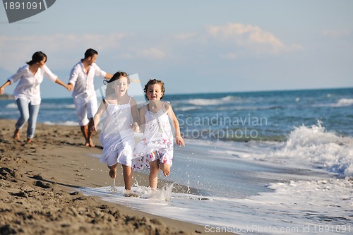 Image of happy family playing with dog on beach