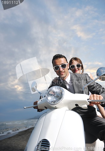 Image of just married couple on the beach ride white scooter