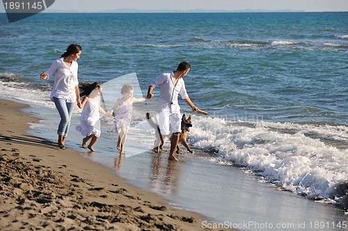 Image of happy family playing with dog on beach