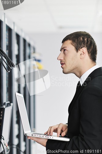 Image of businessman with laptop in network server room