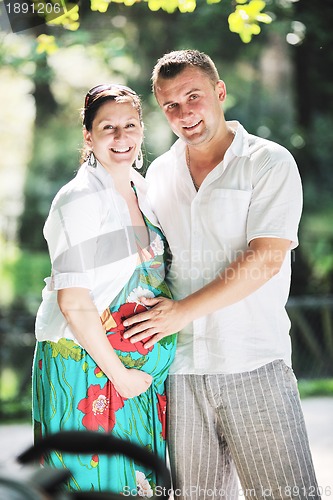 Image of Happy pregnant couple at beautiful sunny day in park