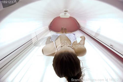 Image of Beautiful young woman tanning in solarium