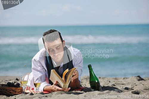 Image of man reading book at beach