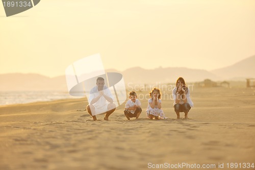 Image of happy young family have fun on beach at sunset