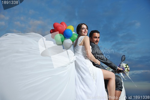 Image of just married couple on the beach ride white scooter