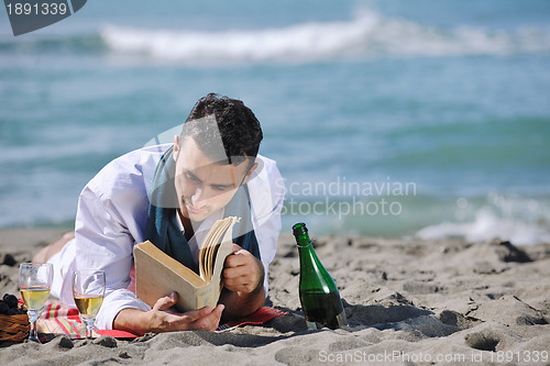 Image of man reading book at beach