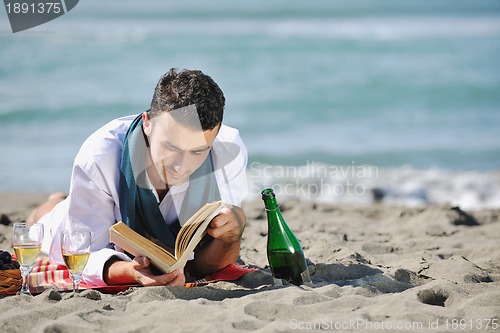Image of man reading book at beach