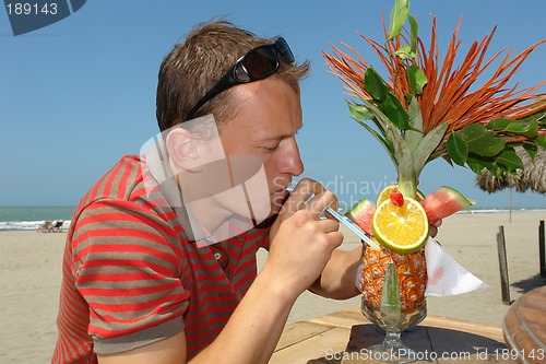 Image of the man drinking a coctail on the beach of pacific ocean