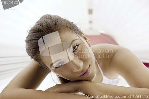 Image of Beautiful young woman tanning in solarium