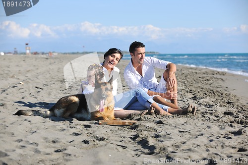 Image of happy family playing with dog on beach