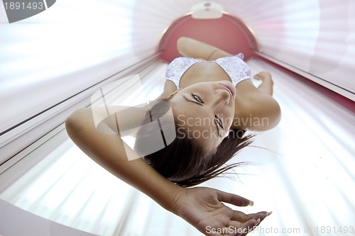 Image of Beautiful young woman tanning in solarium