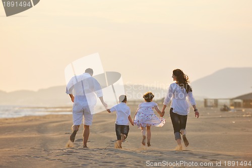 Image of happy young family have fun on beach at sunset