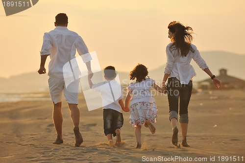 Image of happy young family have fun on beach at sunset
