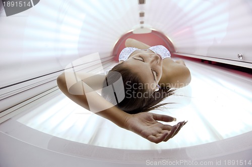 Image of Beautiful young woman tanning in solarium