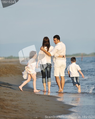 Image of happy young family have fun on beach at sunset