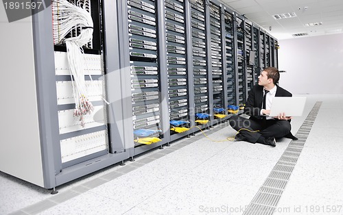 Image of businessman with laptop in network server room