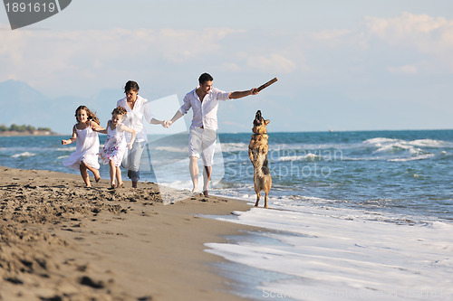 Image of happy family playing with dog on beach