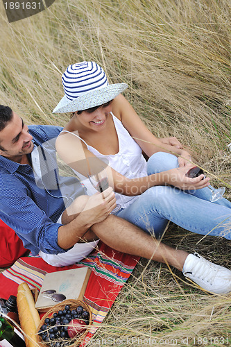 Image of happy couple enjoying countryside picnic in long grass