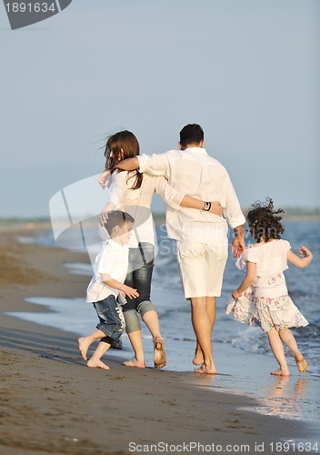 Image of happy young family have fun on beach at sunset